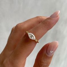 a woman's hand with a diamond ring on top of her finger, against a white background