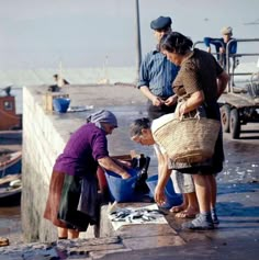 three people are standing near the water with buckets