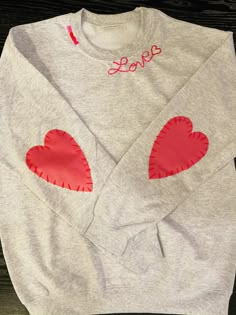 a gray sweater with red hearts on the front and pink heart appliqued on the back