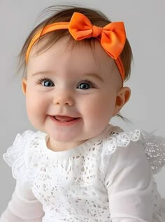 a smiling baby with an orange bow on her head