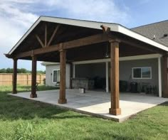 a covered patio in the middle of a yard with an attached grilling area and picnic table