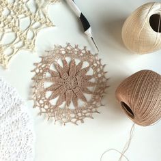 crocheted doily, ball of yarn and scissors on a table with balls of thread