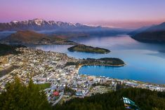 an aerial view of a city and lake with mountains in the background at sunset or dawn