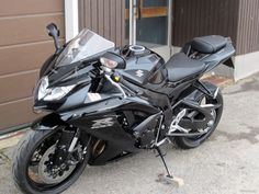 a black motorcycle parked in front of a garage