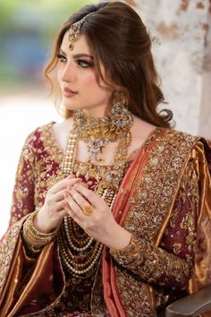 a woman in a red and gold outfit is holding her hands together while sitting down