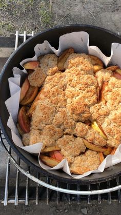 an apple cobbler sitting on top of a grill next to a basket filled with apples