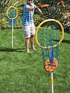 a man is throwing frisbees in the yard with two other people behind him