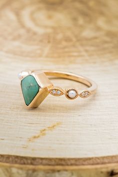 a close up of a ring on a wooden surface with a diamond and turquoise stone in the middle