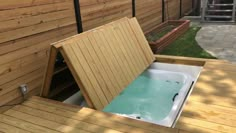 a hot tub sitting on top of a wooden deck next to a fenced in area