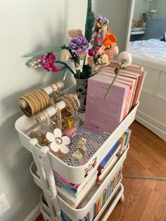 a white cart filled with lots of items on top of a hard wood floor next to a bed