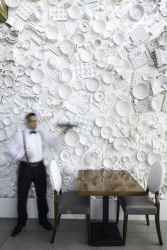 a man standing in front of a wall covered with plates