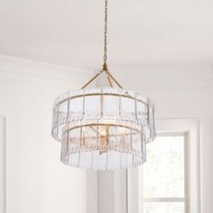 a chandelier hanging from the ceiling in a room with white walls and windows