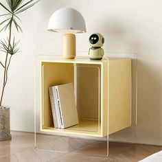 a yellow cube shelf with a lamp and books on it next to a potted plant