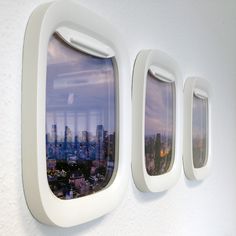 three windows on the side of a wall with cityscape seen through one window