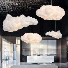 three white clouds hanging from the ceiling in a room with black walls and flooring