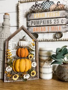 a wooden house with pumpkins and sunflowers in it sitting on a shelf