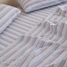 an unmade bed with striped sheets and pillows