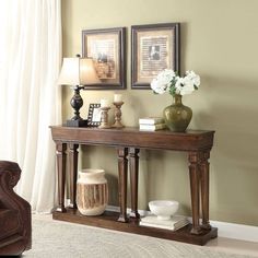 a wooden table with two vases on top of it and pictures above the table