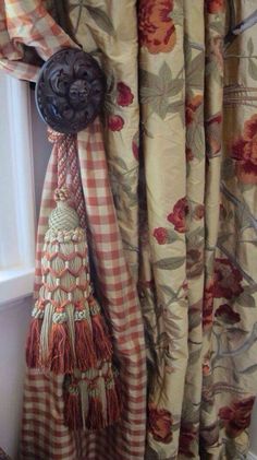 the curtains are hanging on the window sill with tassels and other decorations