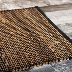 a brown and black rug sitting on top of a wooden floor next to a wall