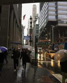 people walking down the street in the rain with umbrellas