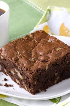 a piece of brownie on a plate next to a cup of coffee