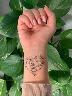 a woman's arm with a flower tattoo on the left side of her wrist