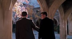 two men in suits are walking through an archway