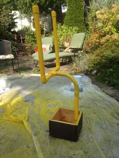 a yellow pipe is attached to a wooden box in the middle of a backyard area