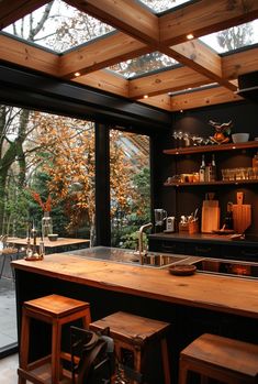 an open kitchen with lots of counter space and wooden furniture in front of large windows