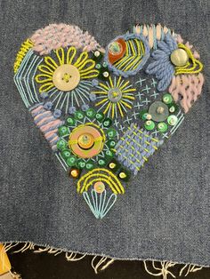 a heart made out of buttons sitting on top of a piece of denim