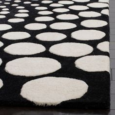 a black and white rug with lots of circles on the floor in front of it