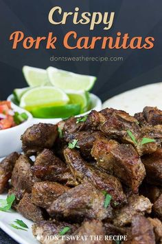 crispy pork carnitas on a white plate with limes and cilantro