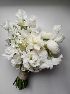 a bouquet of white flowers sitting on top of a gray table next to a wall