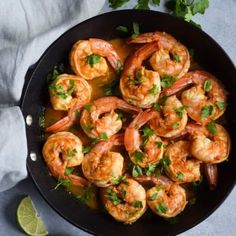 cooked shrimp with cilantro sauce in a skillet next to lime wedges