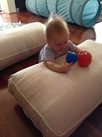 a baby playing with a ball on top of a cushioned chair in the living room