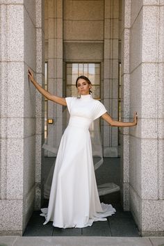 a woman in a white dress is posing for the camera with her arms spread out