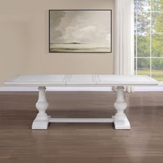 a white dining table sitting on top of a hard wood floor next to a window