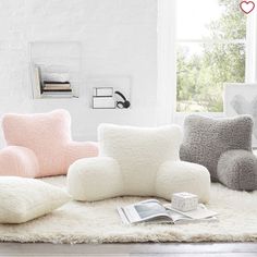 a living room filled with lots of furniture and pillows on top of a white rug