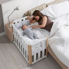 a woman laying in bed next to a baby sleeping in it's crib