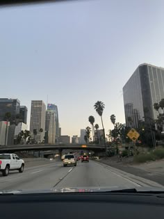 cars driving down the highway in front of tall buildings with palm trees on both sides