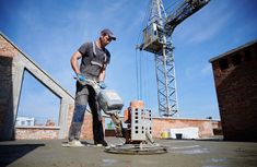 a man is using a concrete mixer on top of a building