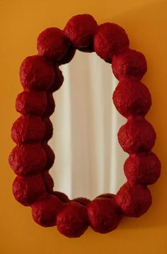 a round mirror mounted to the side of a yellow wall next to a red wall