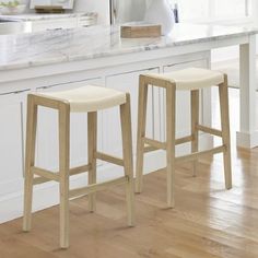 two white stools sitting in front of a kitchen counter