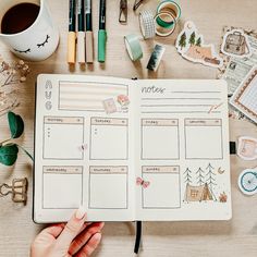 a person is holding a planner and looking at it on a table with other items