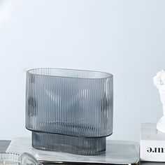 a clear glass vase sitting on top of a table next to some books and candles