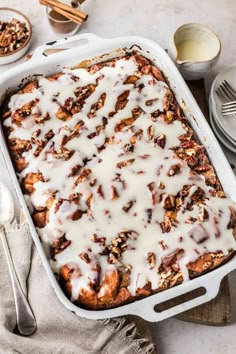 a casserole dish filled with cinnamon rolls and cream cheese drizzled on top