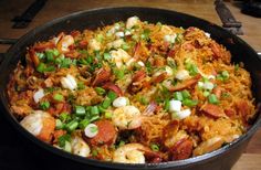 a pan filled with shrimp and rice on top of a wooden table