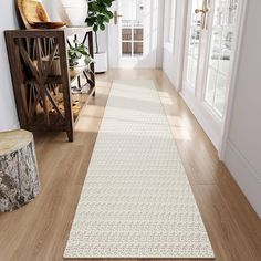 a long white rug on the floor in a room with wooden floors and large windows