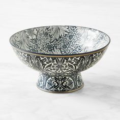 an ornate bowl is sitting on a marble surface